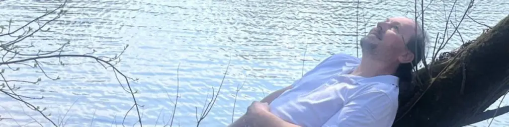 Ursachen von Symptomen – Mann entspannt am Wasser in ruhiger Natur