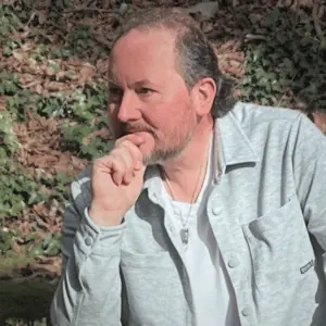 Rückenschmerzen Ursachen, Roland Serias Masin, Begleiter für MetaZentrierung, sitzt in ruhiger Naturumgebung