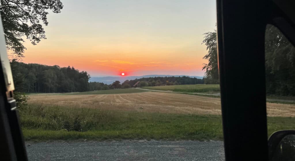 Blick aus dem Wohnmobil auf einen Sonnenuntergang über der Landschaft